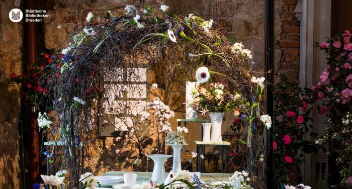 Ein Tisch mit Blumengesteck und Blumenbogen.