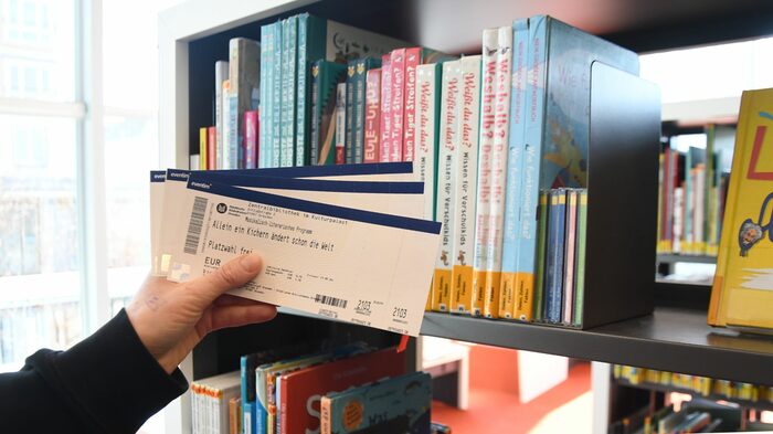 Tickets für Veranstaltungen vor einem Bücherregal.