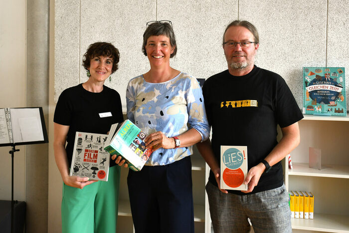 Kinder und Erwachsene vor einem Bücherregal