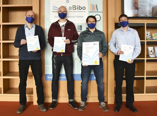 Foto des eBibo-Teams. Vier Männer stehen nebeneinander. Jeder hält eine Urkunde in der Hand.