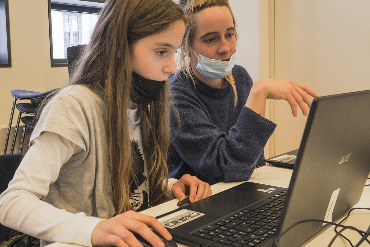 Schüler*innen sitzen vor einem Laptop und arbeiten an dem Spiel.