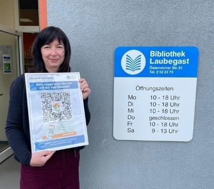 Die Leiterin der Bibliothek Laubegast steht mit einem QR-Code vor der Bibliothek. Die Leiterin der Bibliothek Laubegast steht mit einem QR-Code vor der Bibliothek.