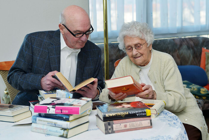 Foto: Ein Mann und eine Frau sitzen mit einem Stapel Bücher an einem Tisch.