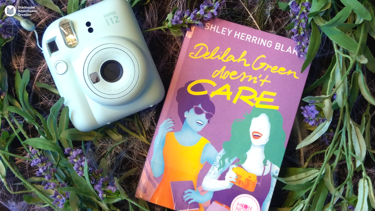 Polaroidkamera und Buch aus Deko-Grünzeug