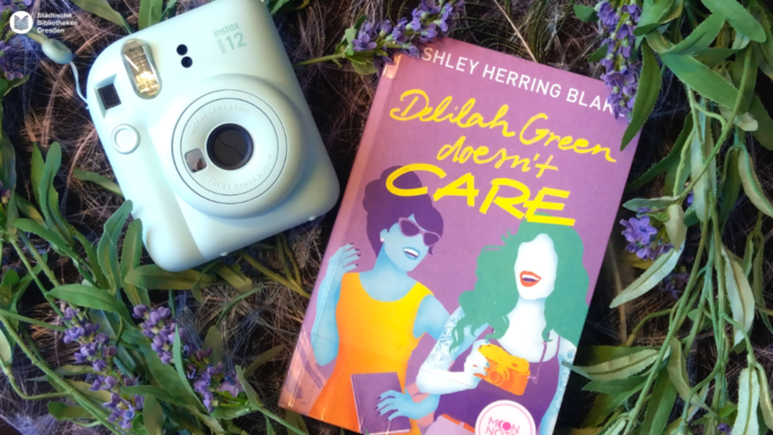 Polaroidkamera und Buch aus Deko-Grünzeug