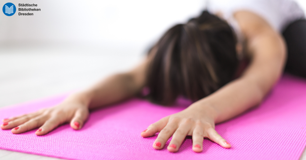 Frau in einer Yogaposition auf einer pinken Matte.