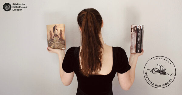 Eine Person ist von hinten zu sehen und hält drei Bücher in den Händen, die zur Kamera gerichtet sind